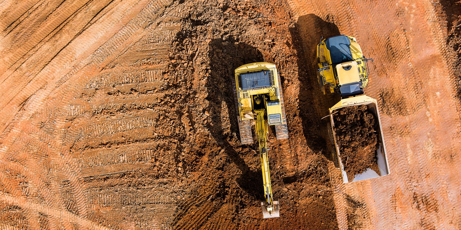 Aerial view on excavators work on construction site dumping earth for loading onto dump trucks